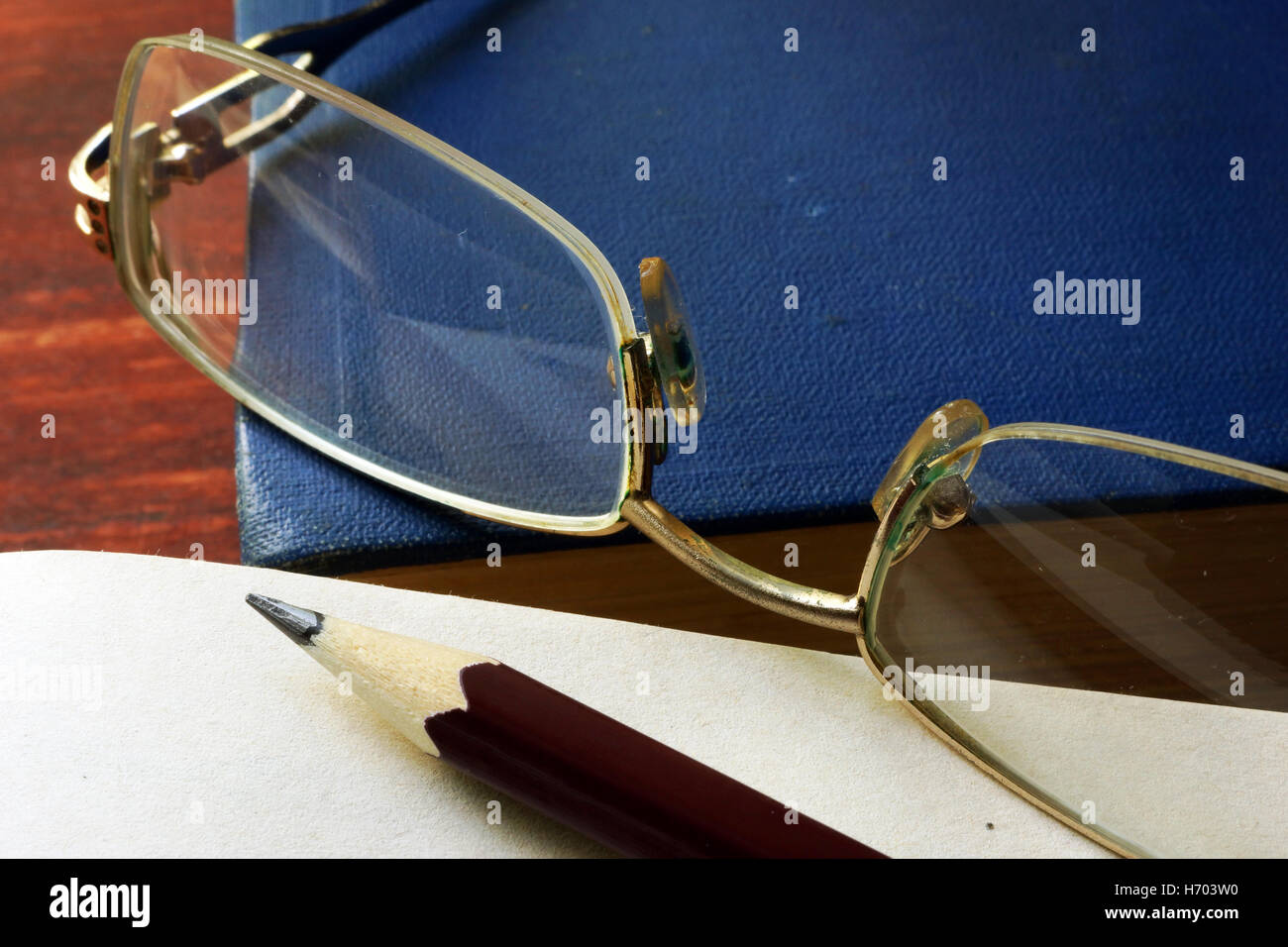 Pencil with notepad and books on wooden table. Stock Photo