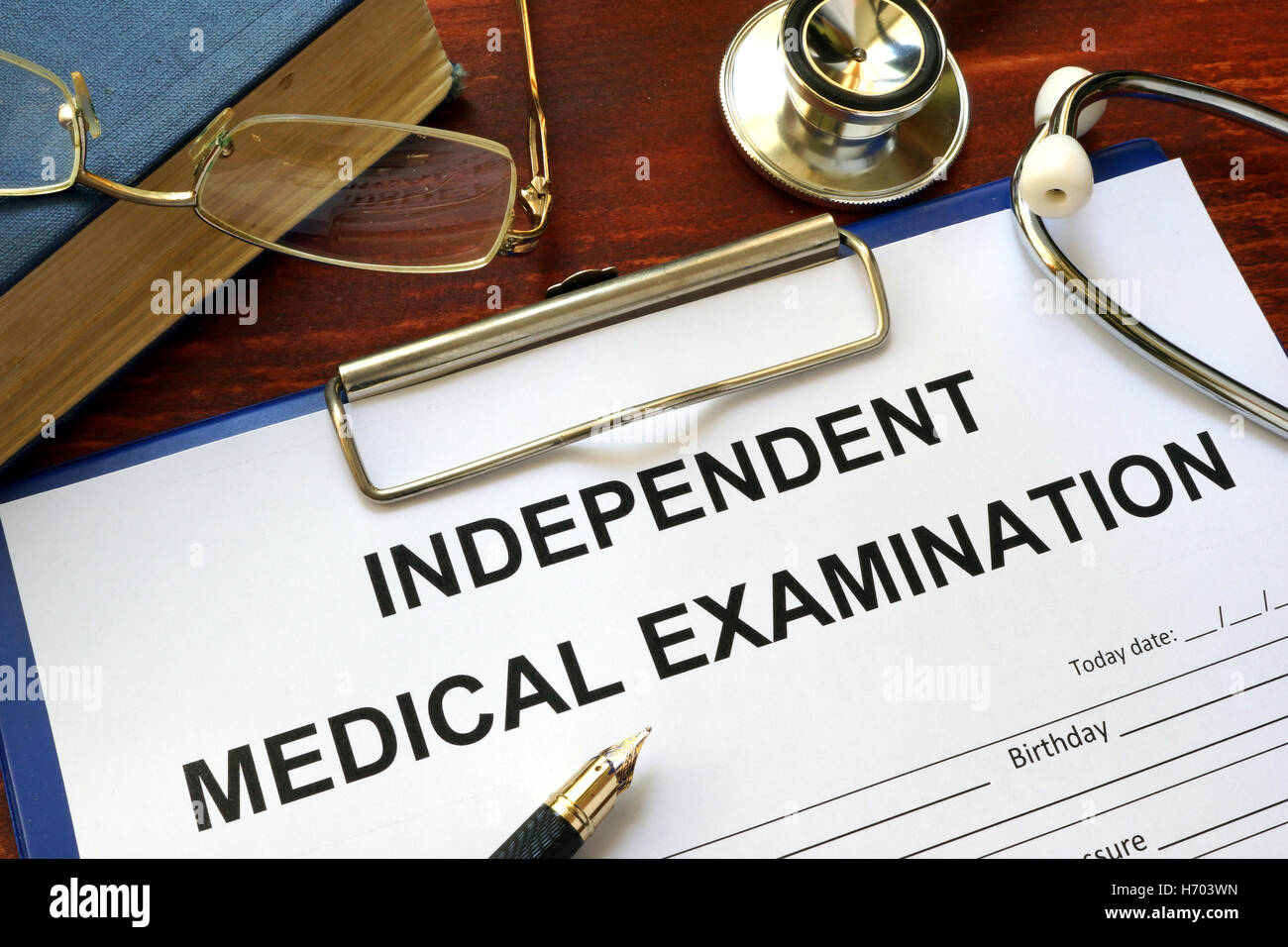 Independent Medical Examination (IME) form on a wooden table. Stock Photo