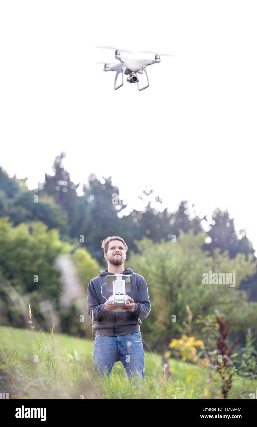 Young hipster man with flying drone. Sunny green nature. Stock Photo