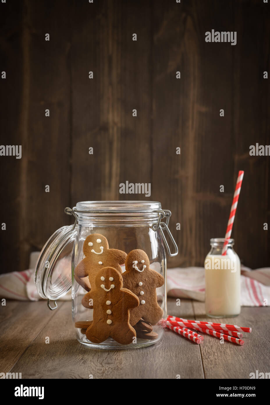 Gingerbread men in cookie jar with milk and straws in the background Stock Photo