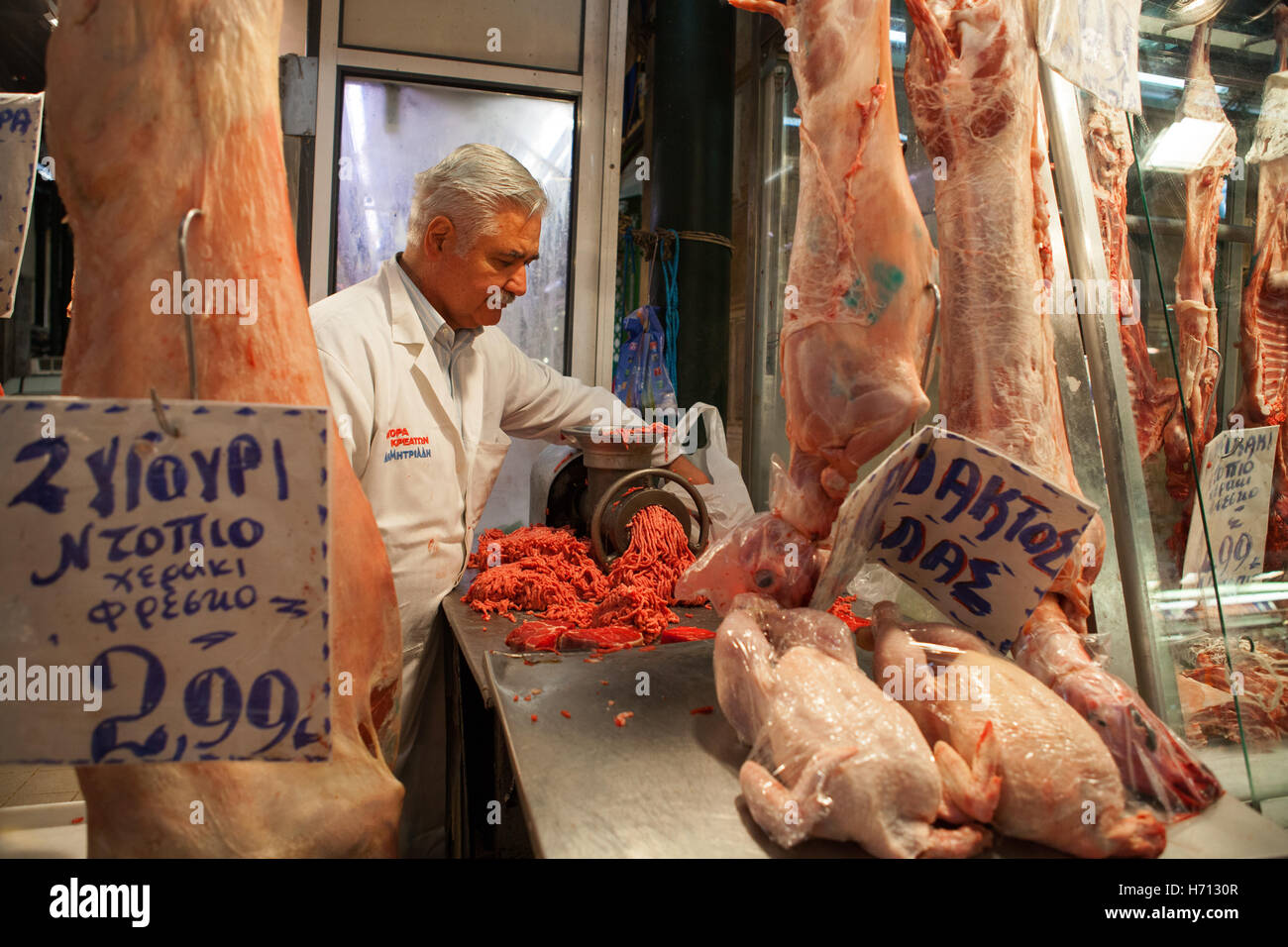A butcher minces meat at his stall in Athens central market Stock Photo