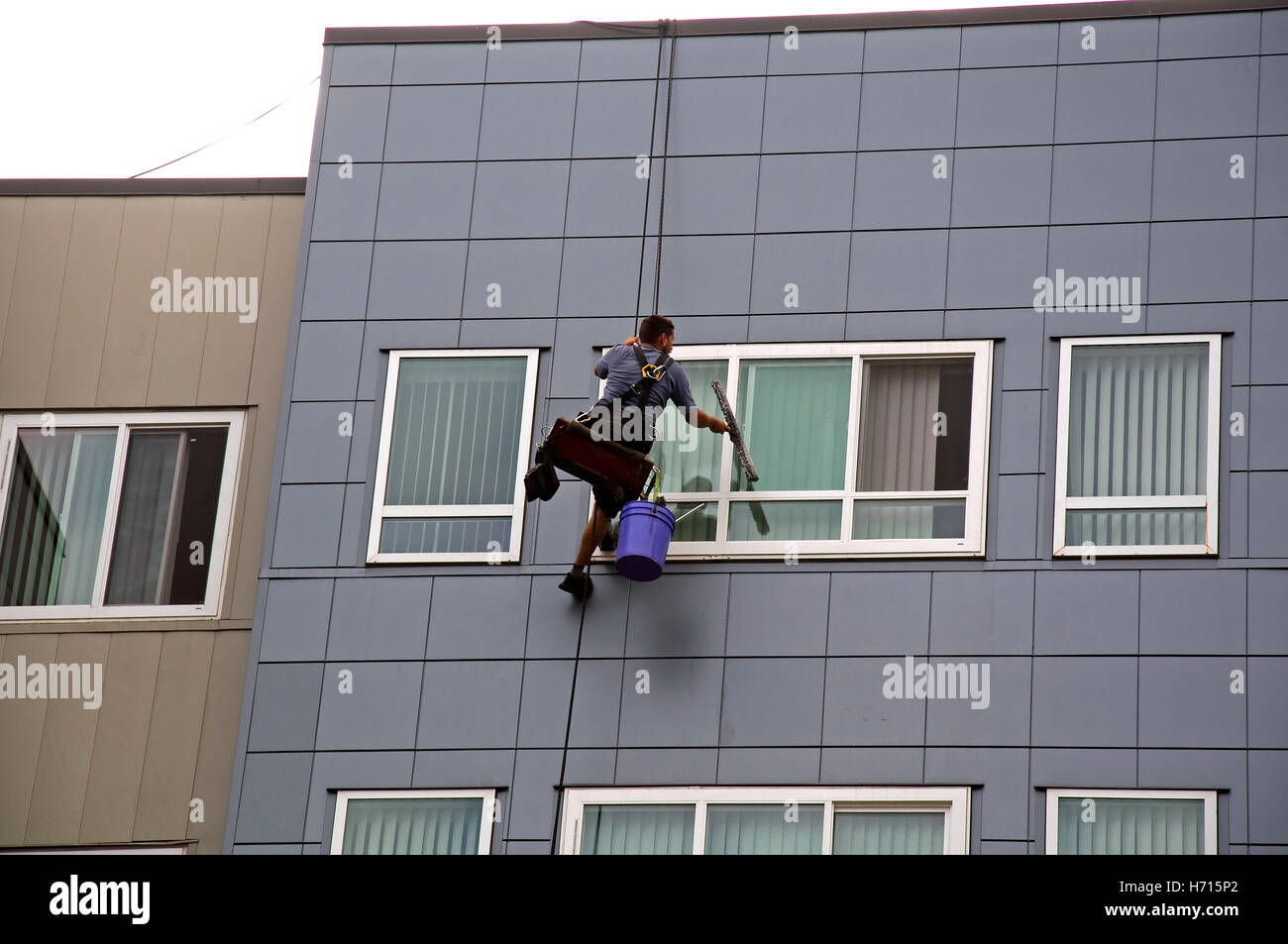 This horizontal image is a man washing windows of a tall building. Stock Photo