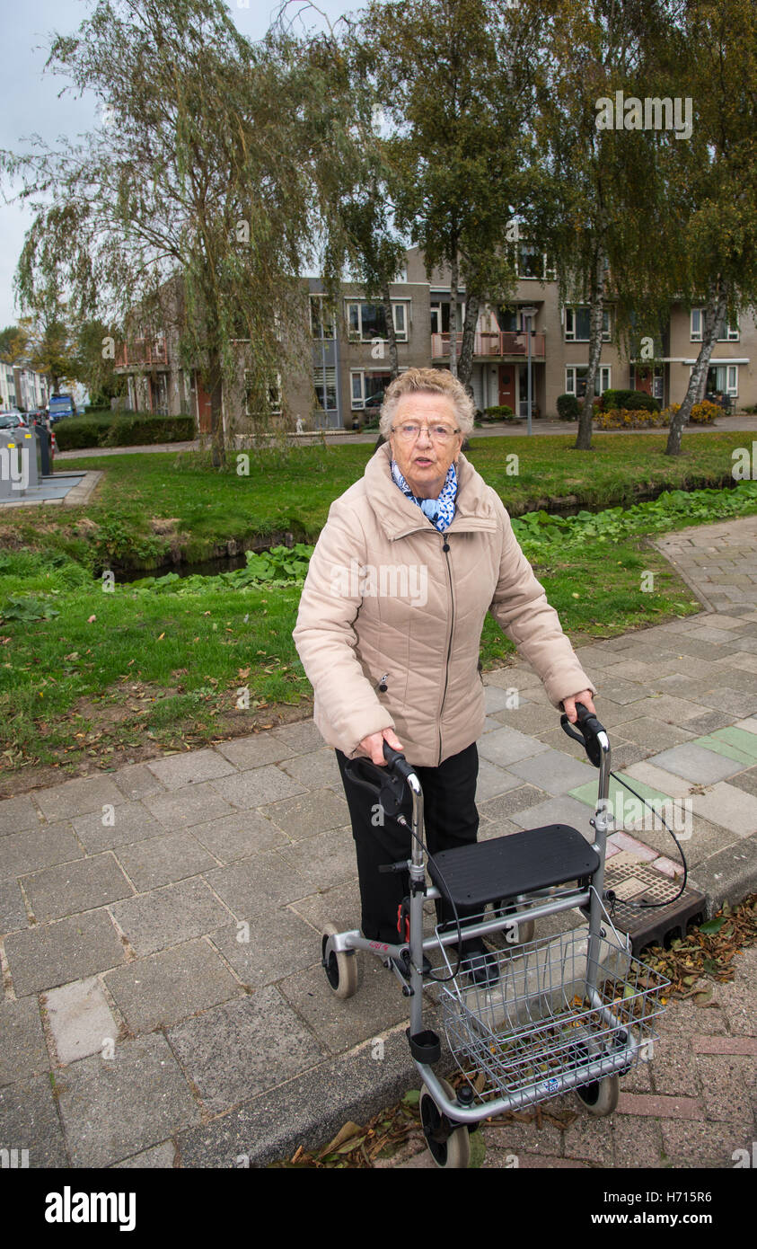 old woman with assist walking on pavement Stock Photo