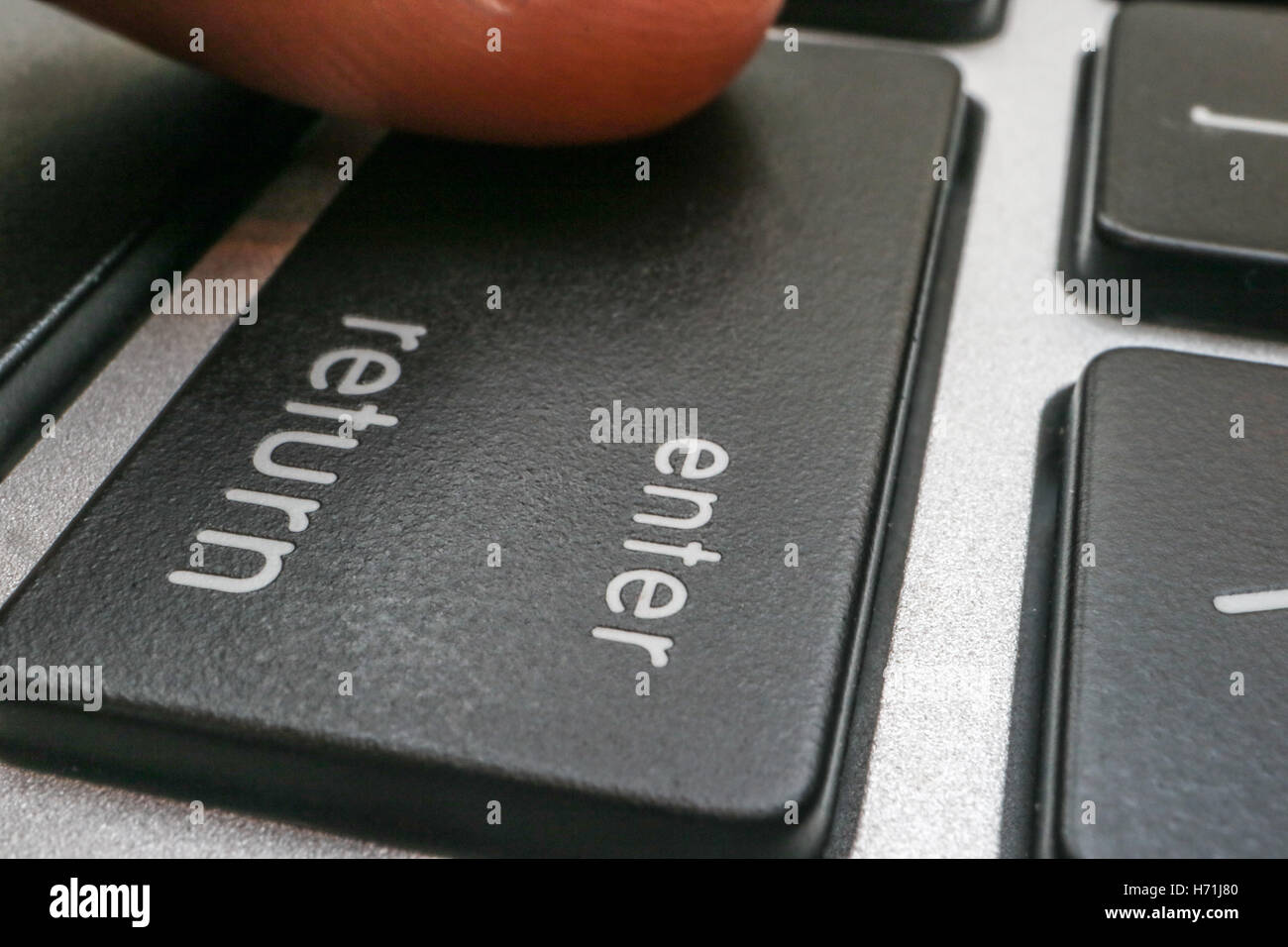 computer enter key with finger pressing button Stock Photo