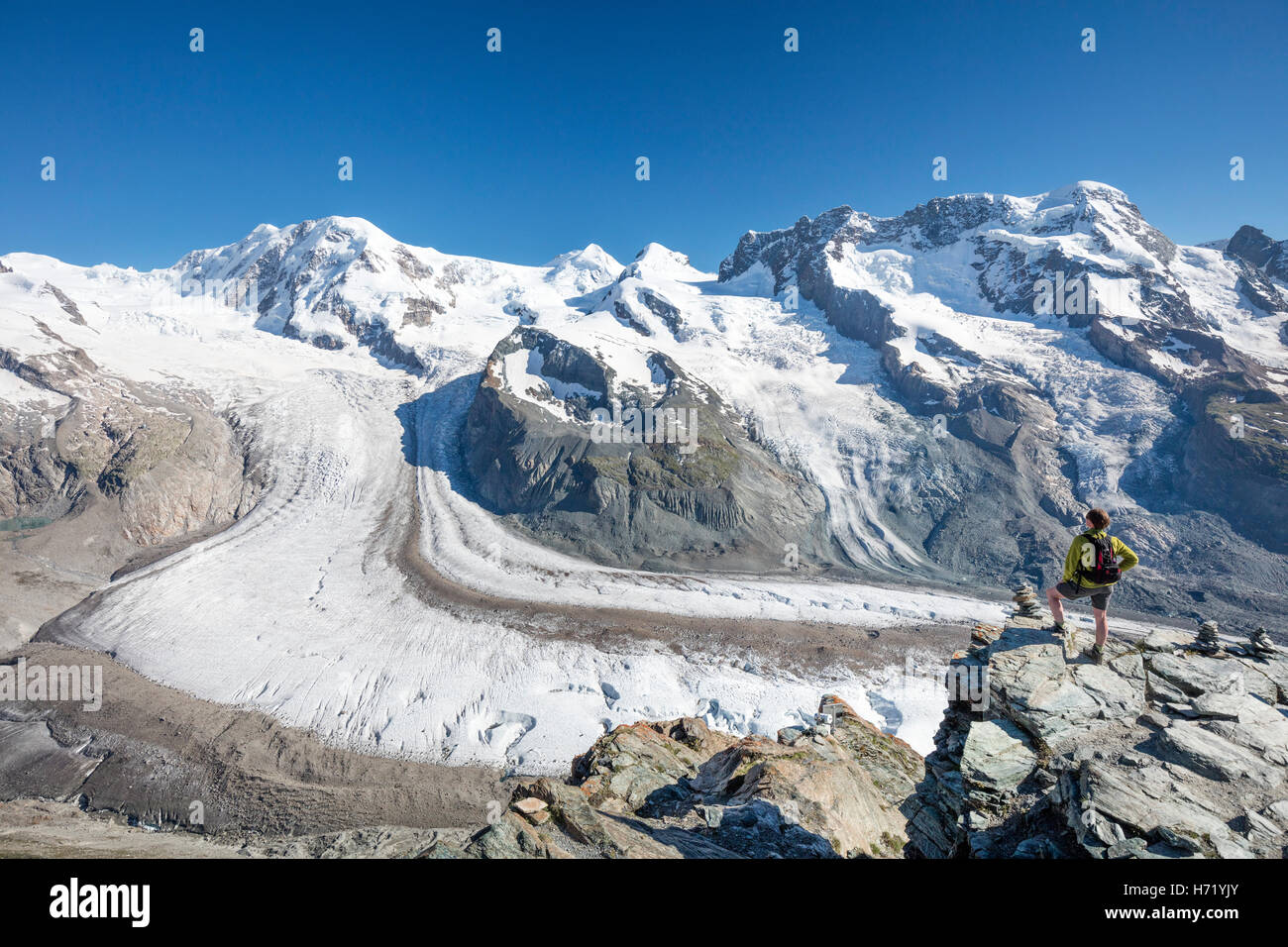 Hiker looking over Gorner Glacier and Monte Rosa from Gornergrat. Zermatt, Pennine Alps, Valais, Switzerland. Stock Photo
