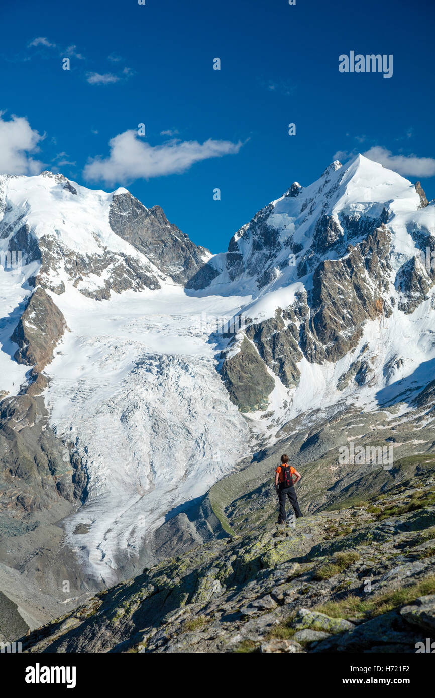 Hiker beneath Piz Bernina and Piz Rosbeg. Fuorcla Surlej, Silvaplana, Berniner Alps, Graubunden, Switzerland. Stock Photo