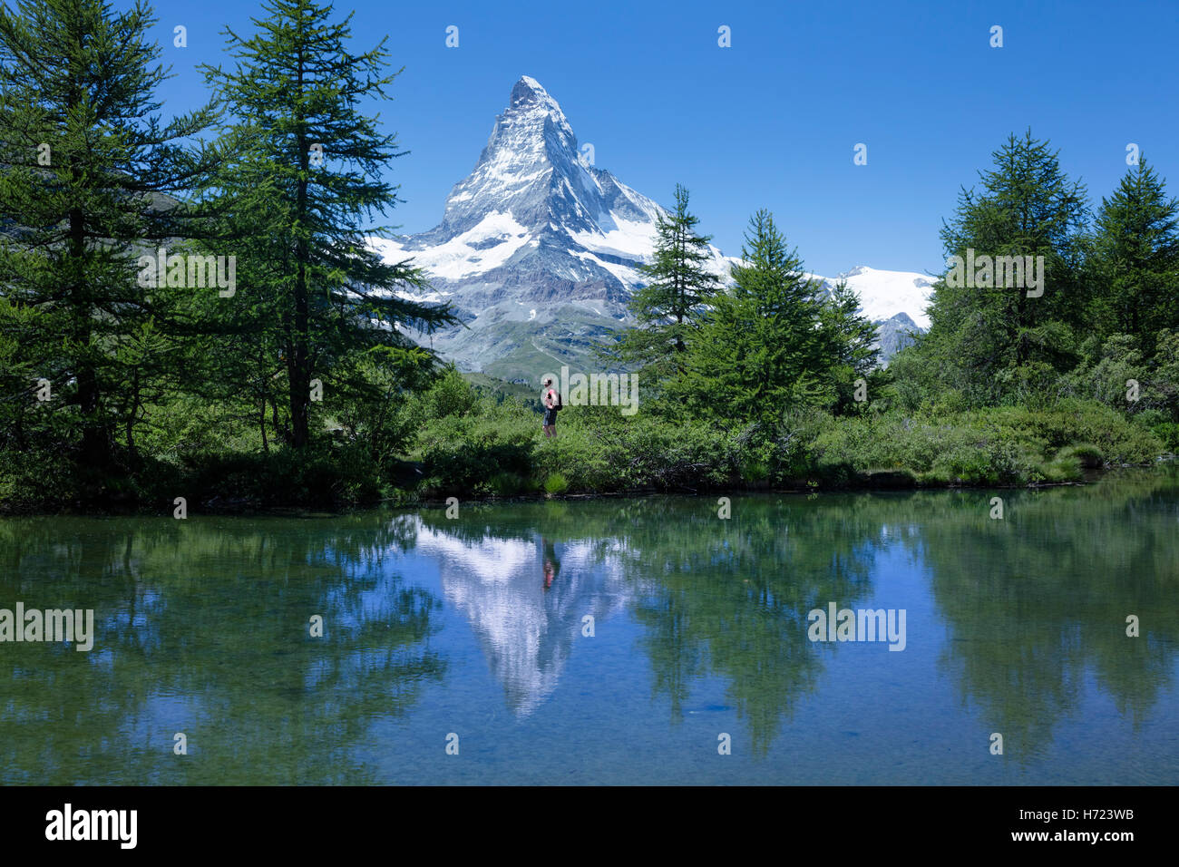 Hiker and Matterhorn reflected in the Grunsee, Zermatt, Pennine Alps, Valais, Switzerland. Stock Photo