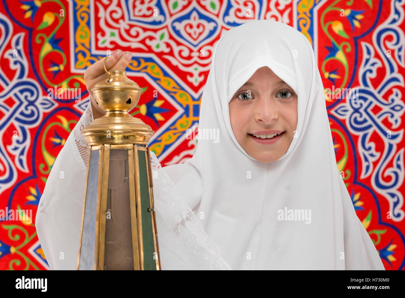 Happy Muslim Girl with Festive Ramadan Lantern over Ramadan Fabric Stock Photo