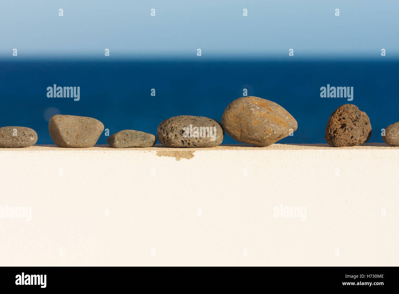 Pebbles on the wall. Ocean in the background Stock Photo