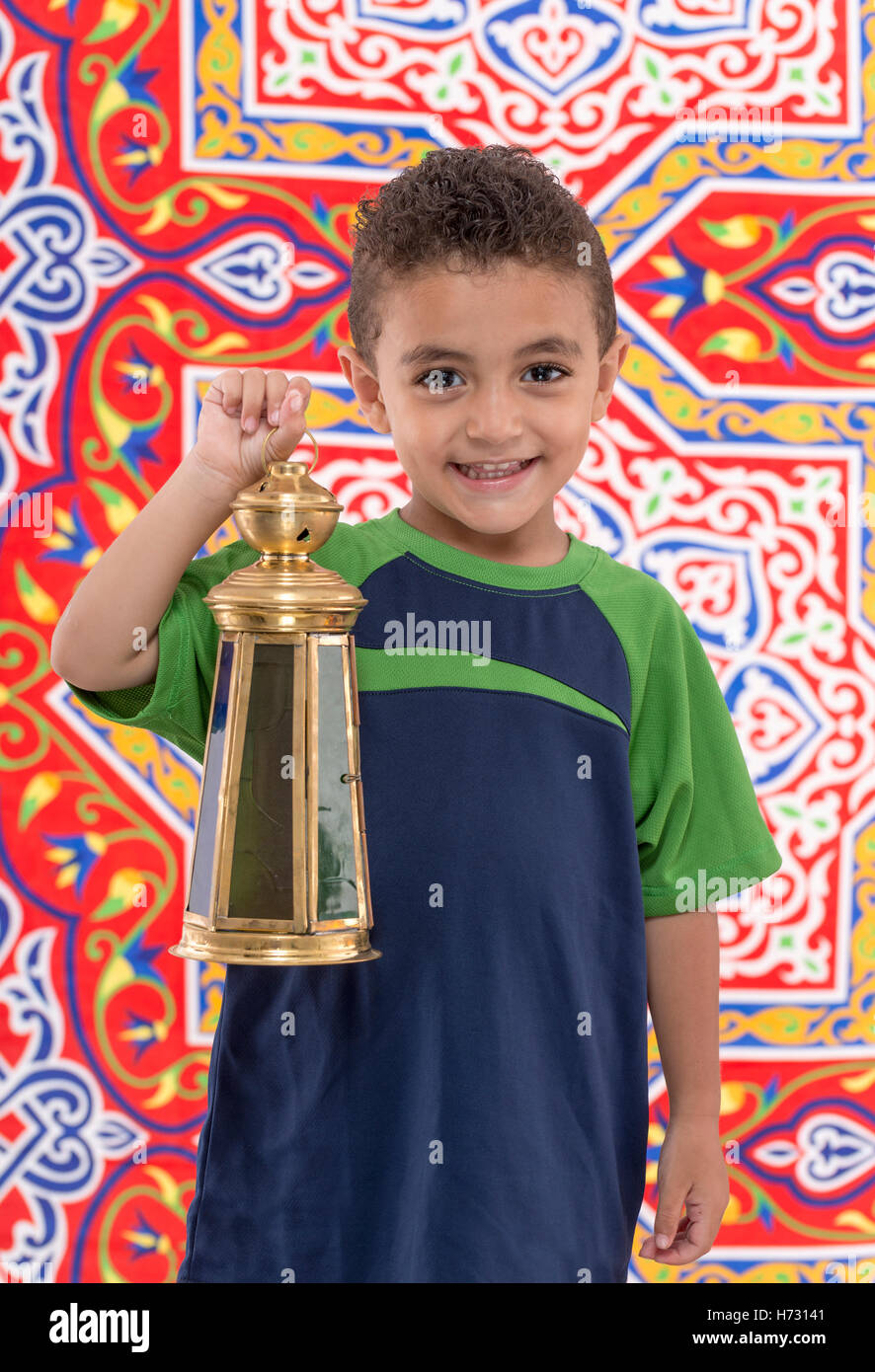 Adorable Young Boy with Vintage Lantern over Festive Ramadan Fabric Stock Photo