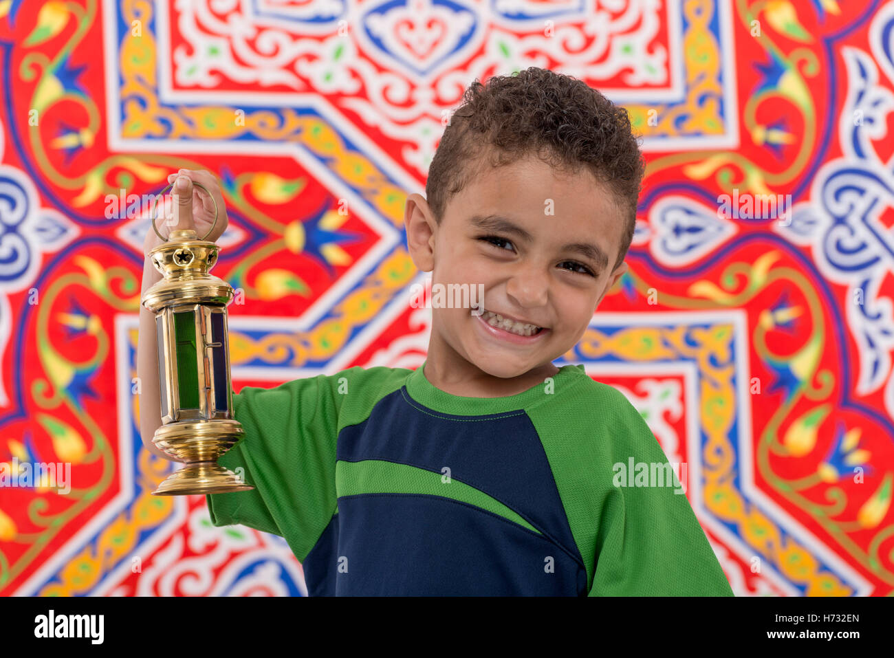 Adorable Smiling Boy with Vintage Lantern over Festive Ramadan Fabric Stock Photo