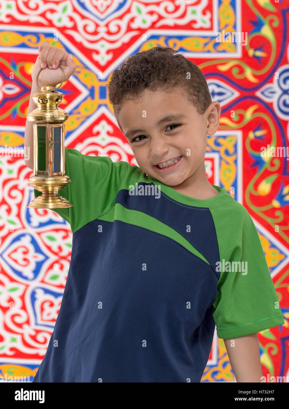 Adorable Young Boy with Small Ramadan Lantern over Ramadan Fabric Stock Photo