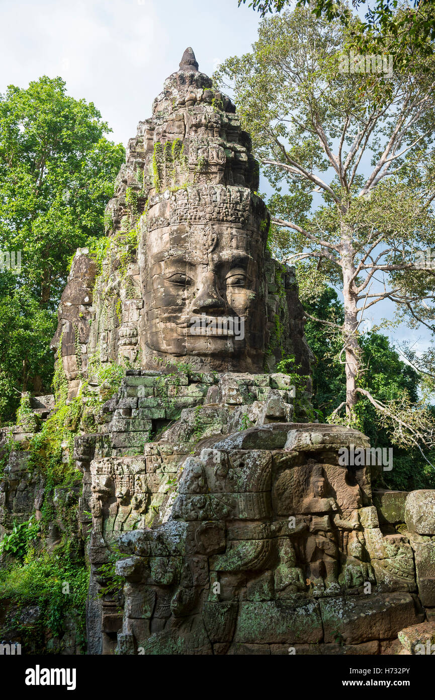 Imposing stone face smiles from the top of the East Gate at Angkor Thom, part of the Angkor Wat temple complex in Cambodia Stock Photo