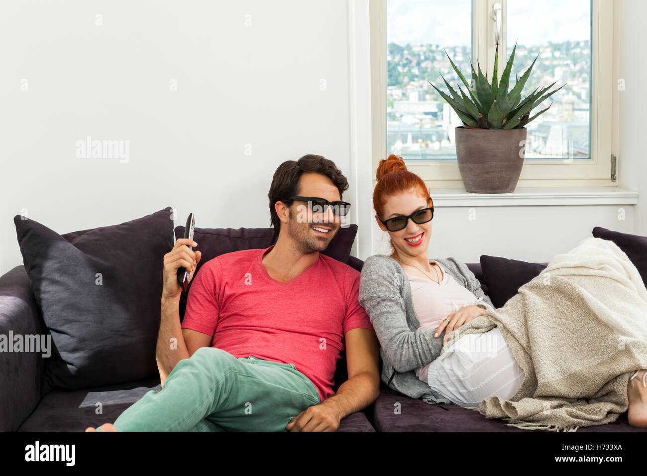 young couple sitting with 3d glasses on the sofa and looks remote Stock Photo