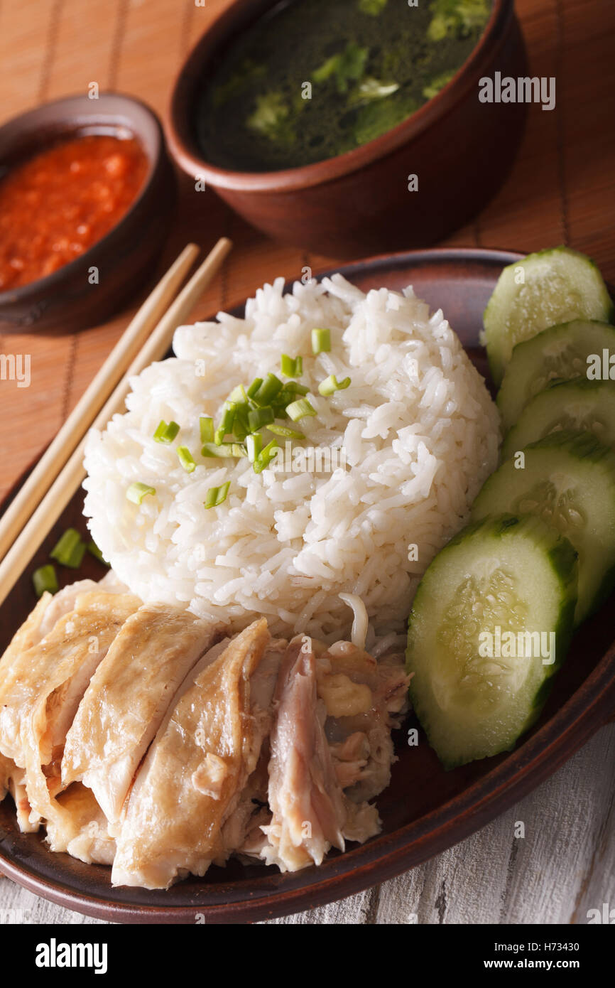 Hainanese chicken rice with cucumber close-up on a table and broth ...