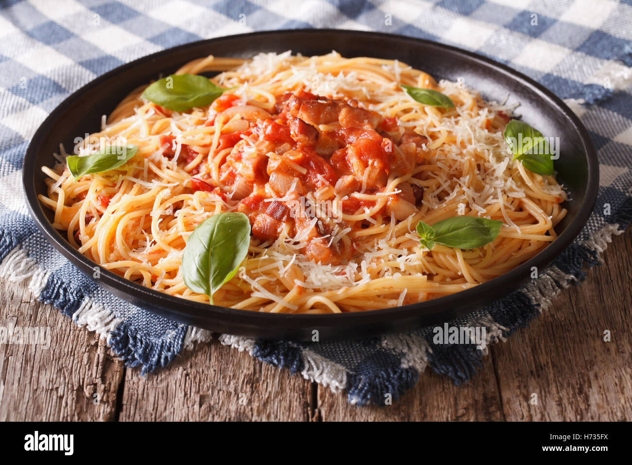 Italian food: pasta with Amatriciana Sauce, cheese and basil close-up on a plate on the table. horizontal Stock Photo