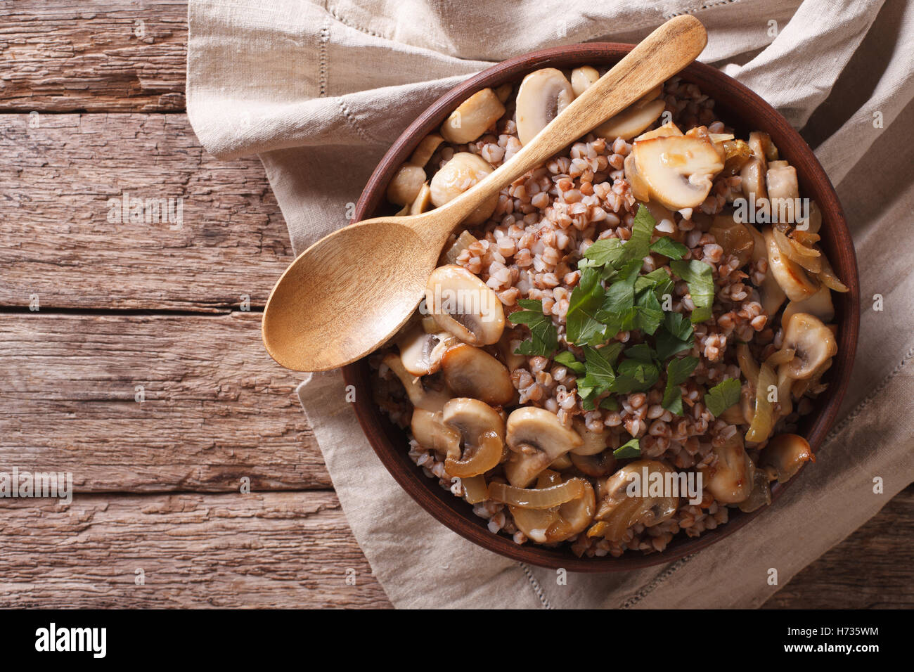 Buckwheat with roasted mushrooms and onions in a bowl on the table. Horizontal view from above Stock Photo