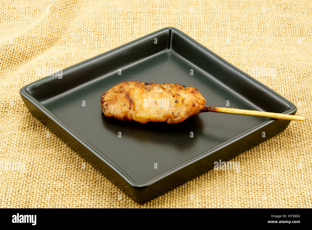 Thai styled pork barbeque in black plate on sackcloth background Stock Photo