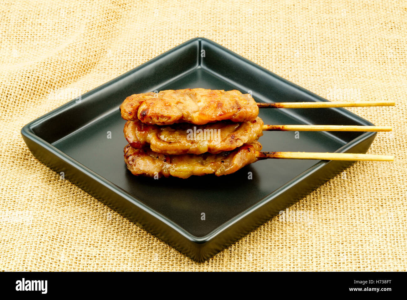 Thai styled pork barbeque in black plate on sackcloth Stock Photo