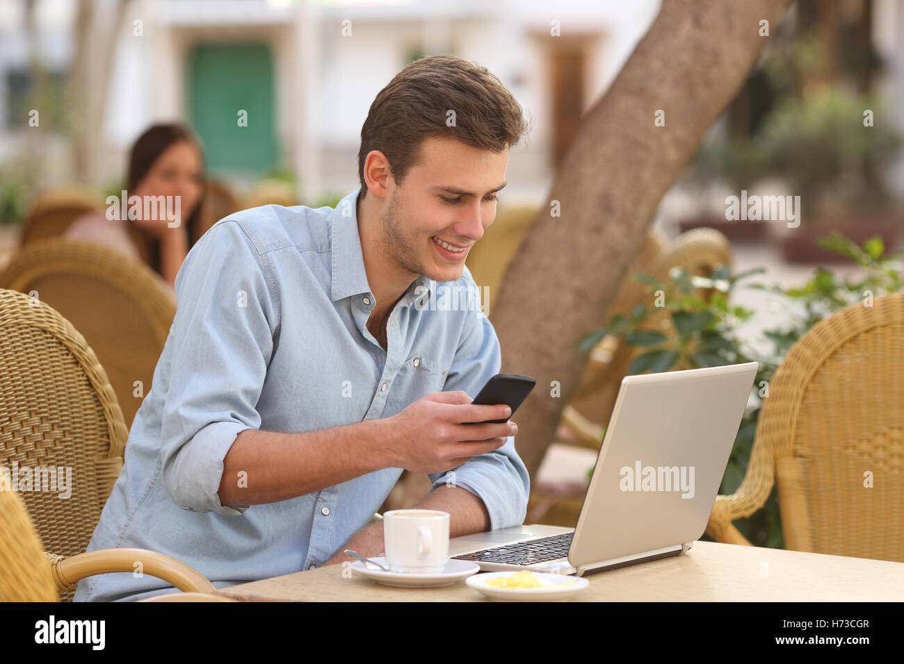 Self employed man working with a laptop and a phone in a restaurant Stock Photo