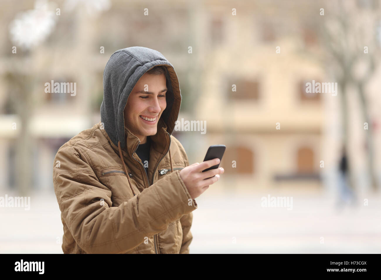 Happy teen walking and using a smart phone Stock Photo