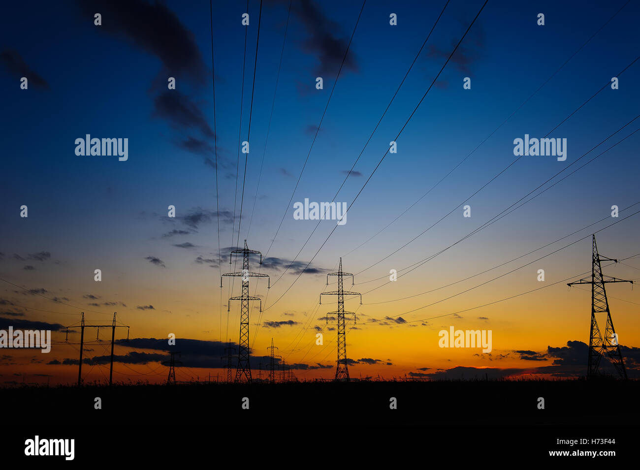 A silhouette of high voltage power lines against a dramatic and ...