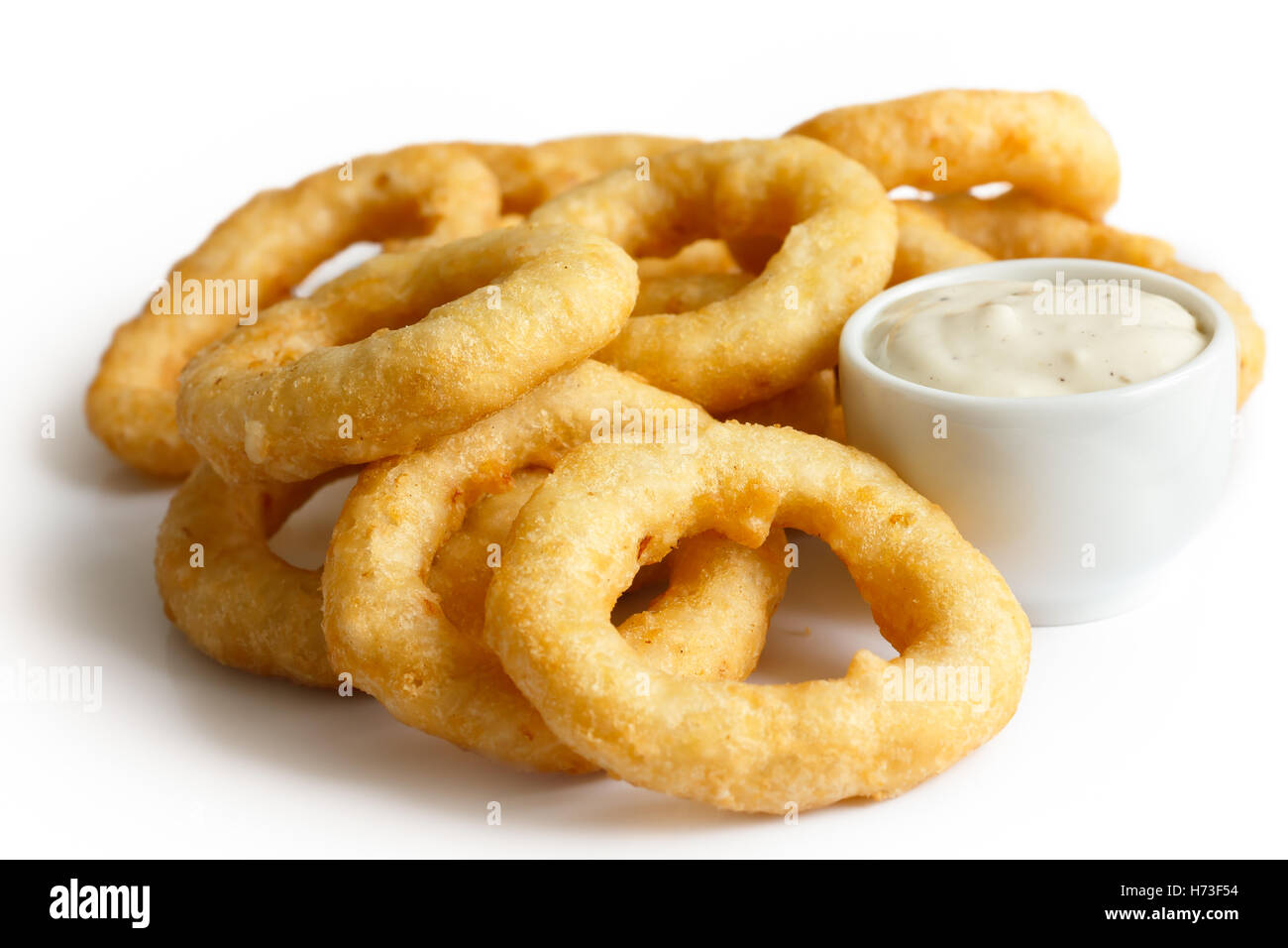 Heap of deep fried onion or calamari rings with garlic mayonnaise dip isolated on white. Stock Photo