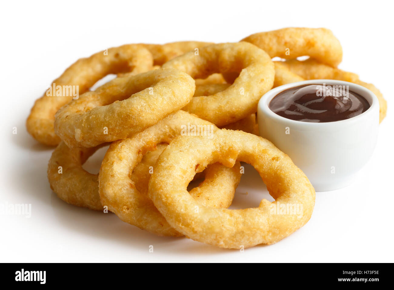 Heap of deep fried onion or calamari rings with barbecue dip isolated on white. Stock Photo