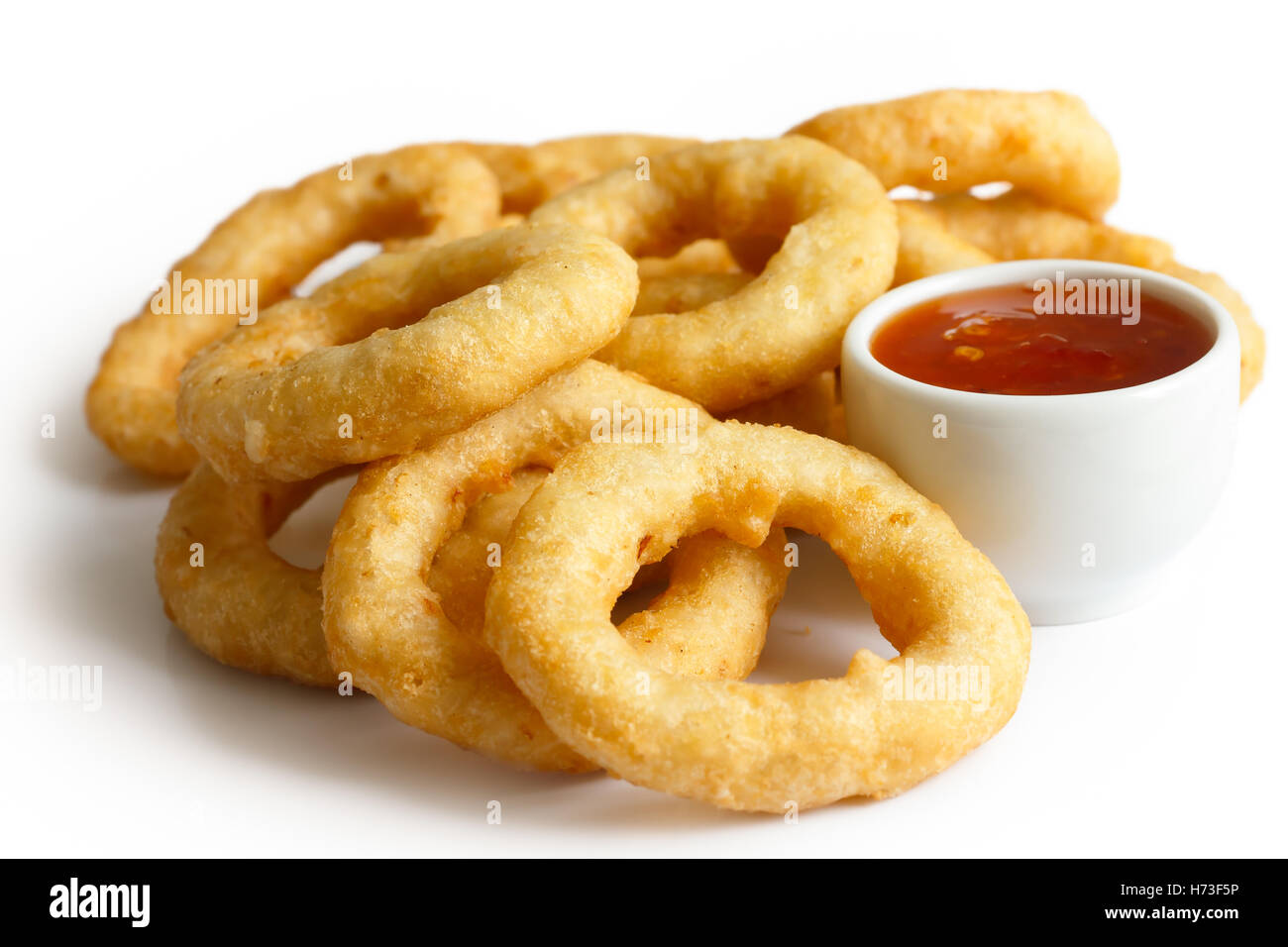 Heap of deep fried onion or calamari rings with chilli dip isolated on white. Stock Photo