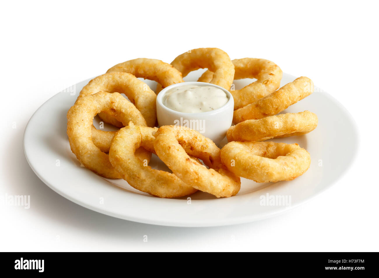 Heap of deep fried onion or calamari rings with garlic mayonnaise dip on white plate. Stock Photo