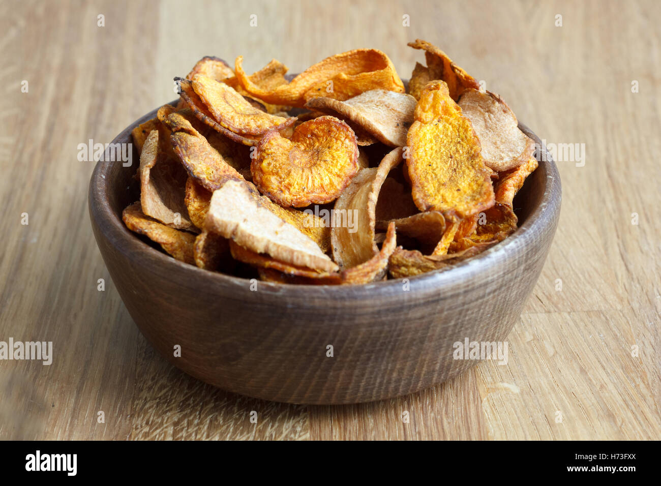 Detail of fried carrot and parsnip chips in rustic wood bowl Stock
