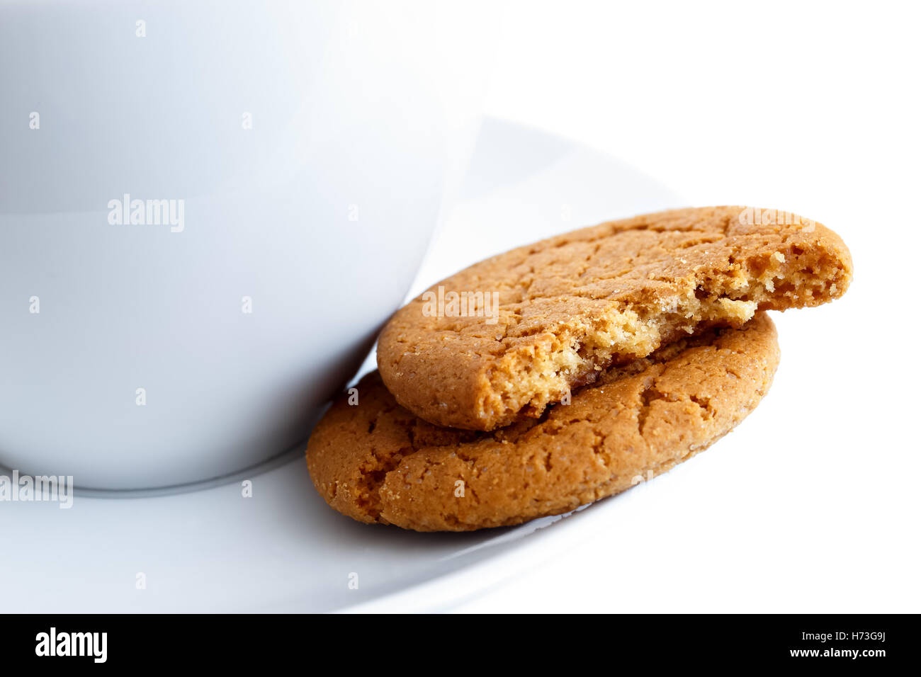 Detail of two ginger biscuits, one broken in half, with cup and saucer