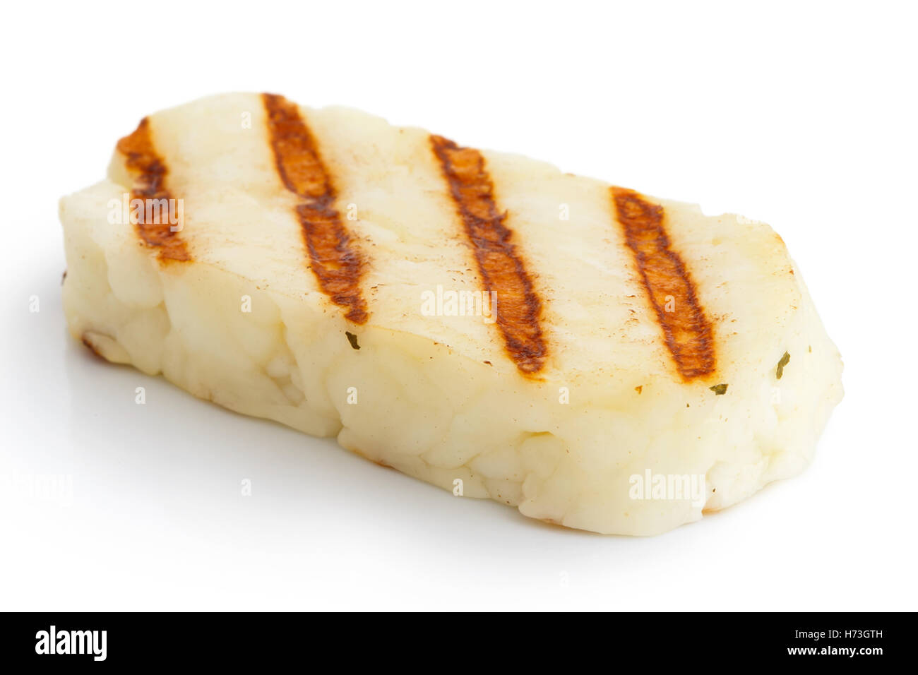 Single grilled slice of halloumi cheese isolated on white in perspective. With grill marks. Stock Photo