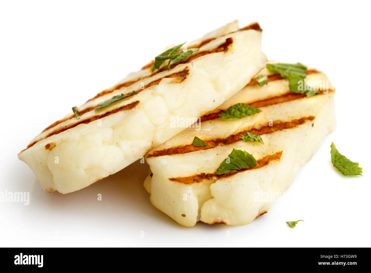 Two grilled slices of halloumi cheese isolated on white in perspective. With grill marks and mint. Stock Photo