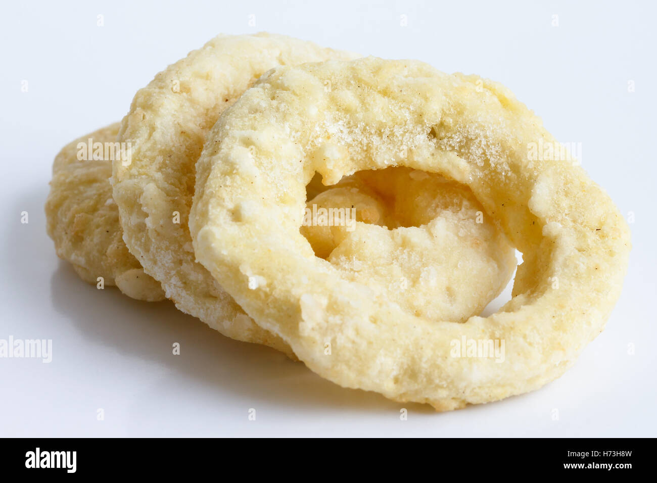 Three frozen uncooked battered onion or calamari rings isolated on grey. Stock Photo