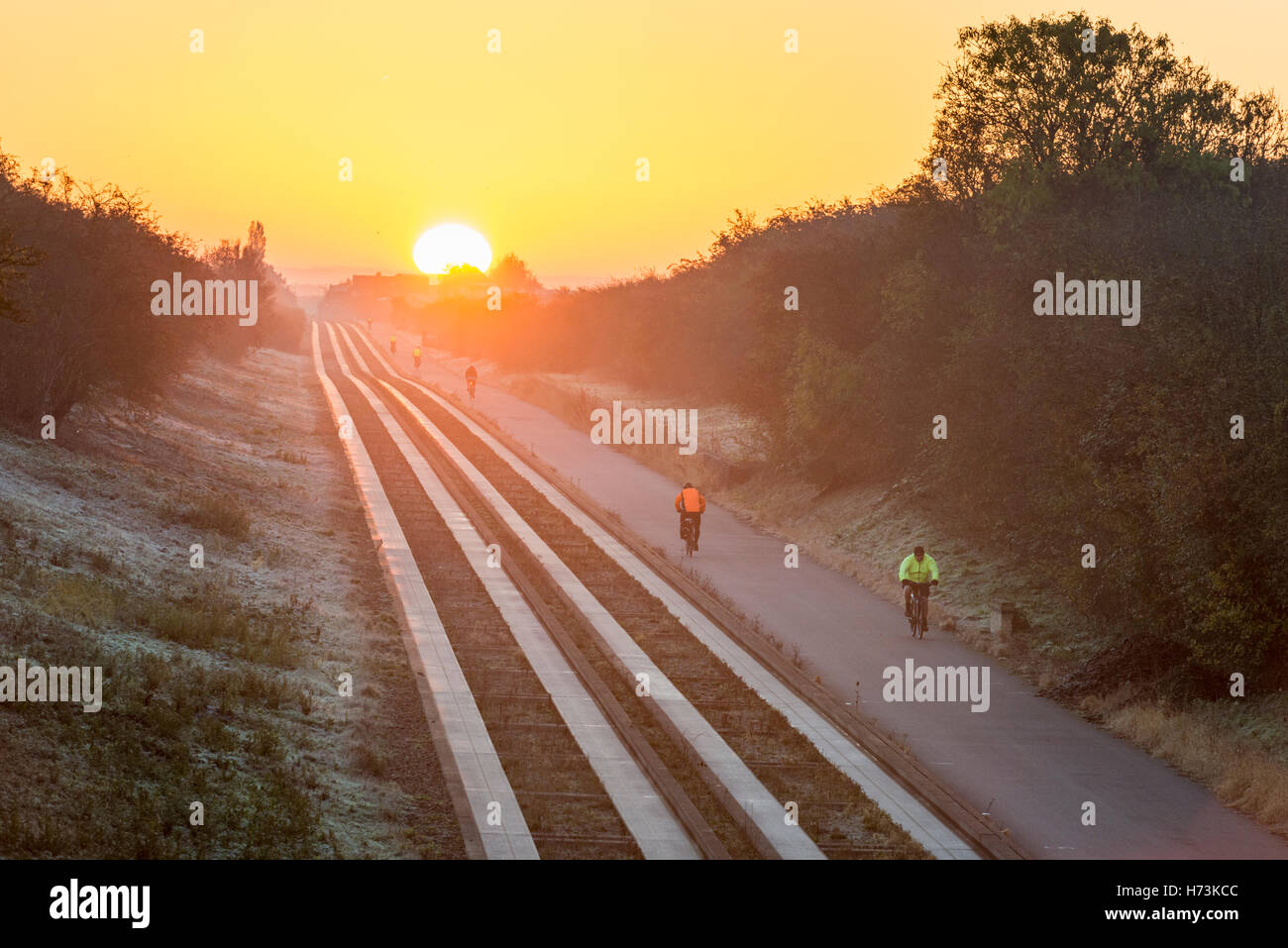 Over, Cambridgeshire UK, 2nd November 2016.  Cyclists ride towards Cambridge as the sun rises over the tracks on a clear, crisp, frosty autumn morning. The clear air and first frost of this autumn in the East of the UK shed a golden glow on the morning commute. Credit Julian Eales/Alamy Live News Stock Photo