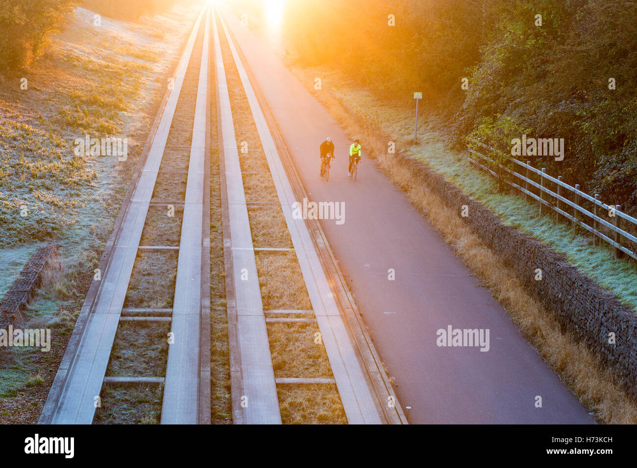Over, Cambridgeshire UK, 2nd November 2016.  Cyclists ride away from Cambridge as the sun rises over the tracks on a clear, crisp, frosty autumn morning. The clear air and first frost of this autumn in the East of the UK shed a golden glow on the morning commute. Credit Julian Eales/Alamy Live News Stock Photo
