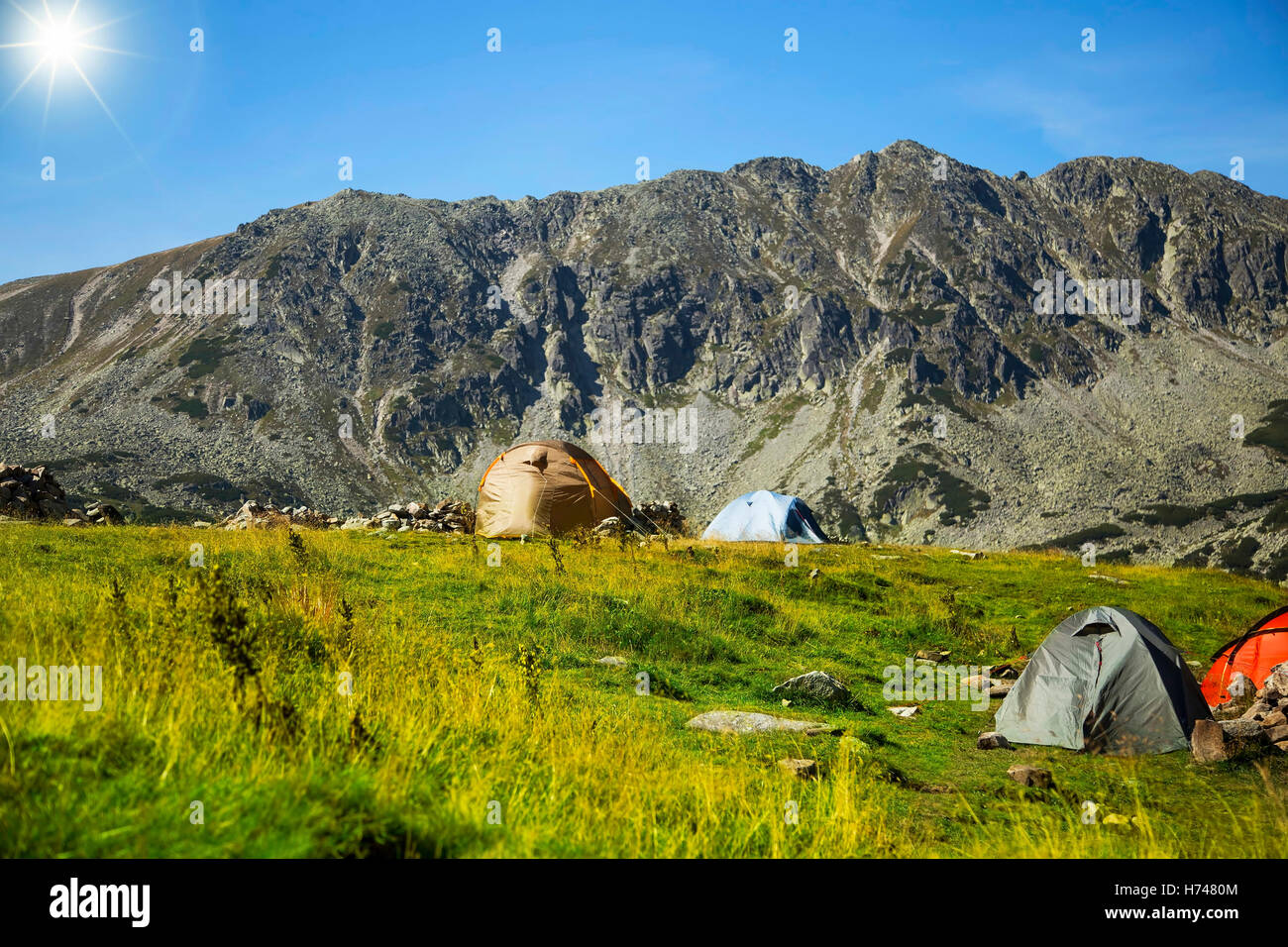 Sunny summer mountain alpine landscape with camping tents Stock Photo
