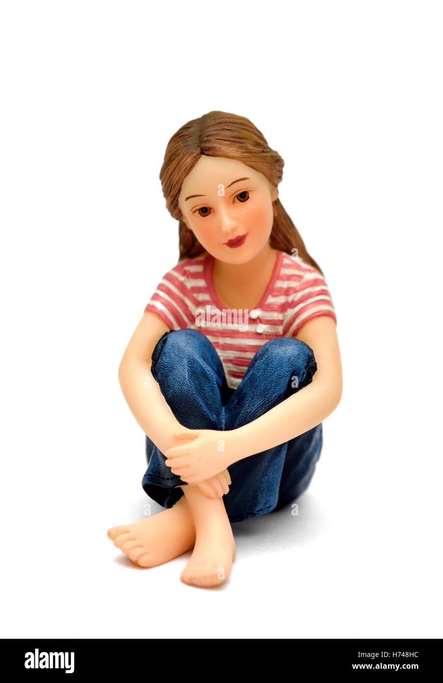 A figurine of a teenage girl sitting down. Stock Photo