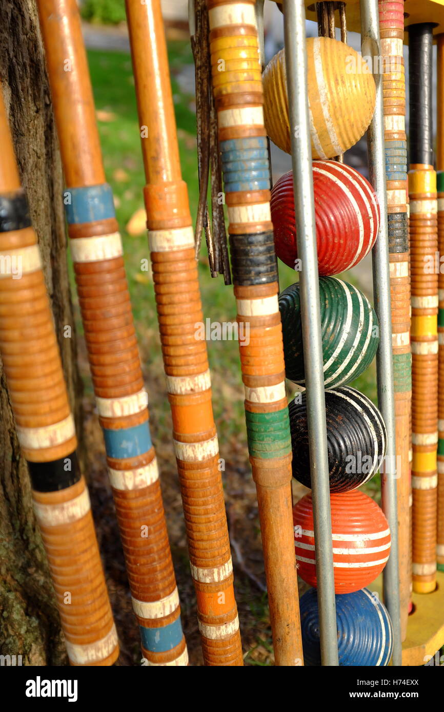 Well-used wooden croquet set standing outside on a summer lawn with its balls and mallets properly stored in its holster. Stock Photo