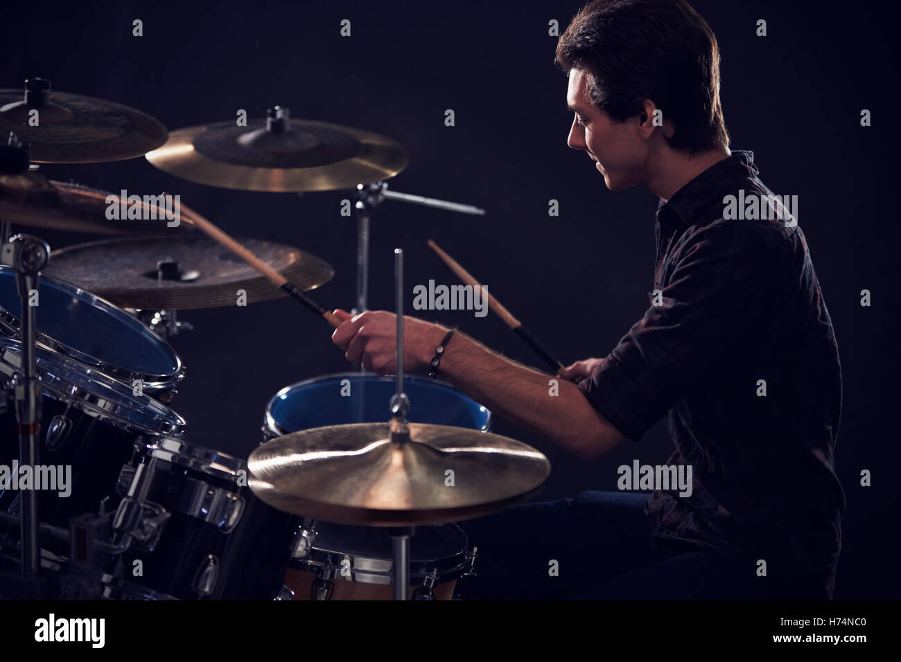 Side View Of Young Drummer Playing Drum Kit In Studio Stock Photo