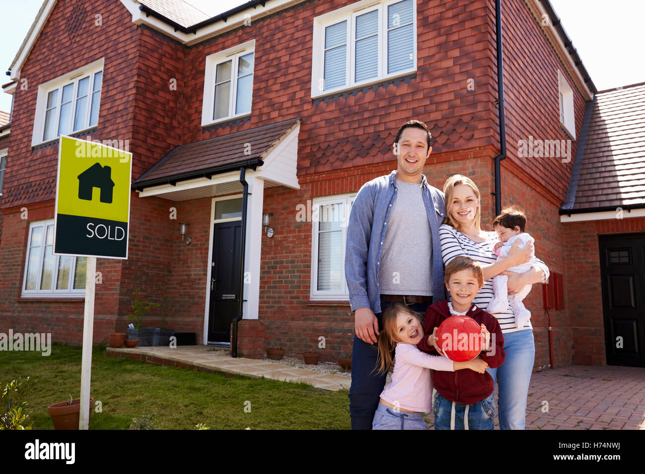 Portrait Of Family Outside New Home With Sold Sign Stock Photo - Alamy
