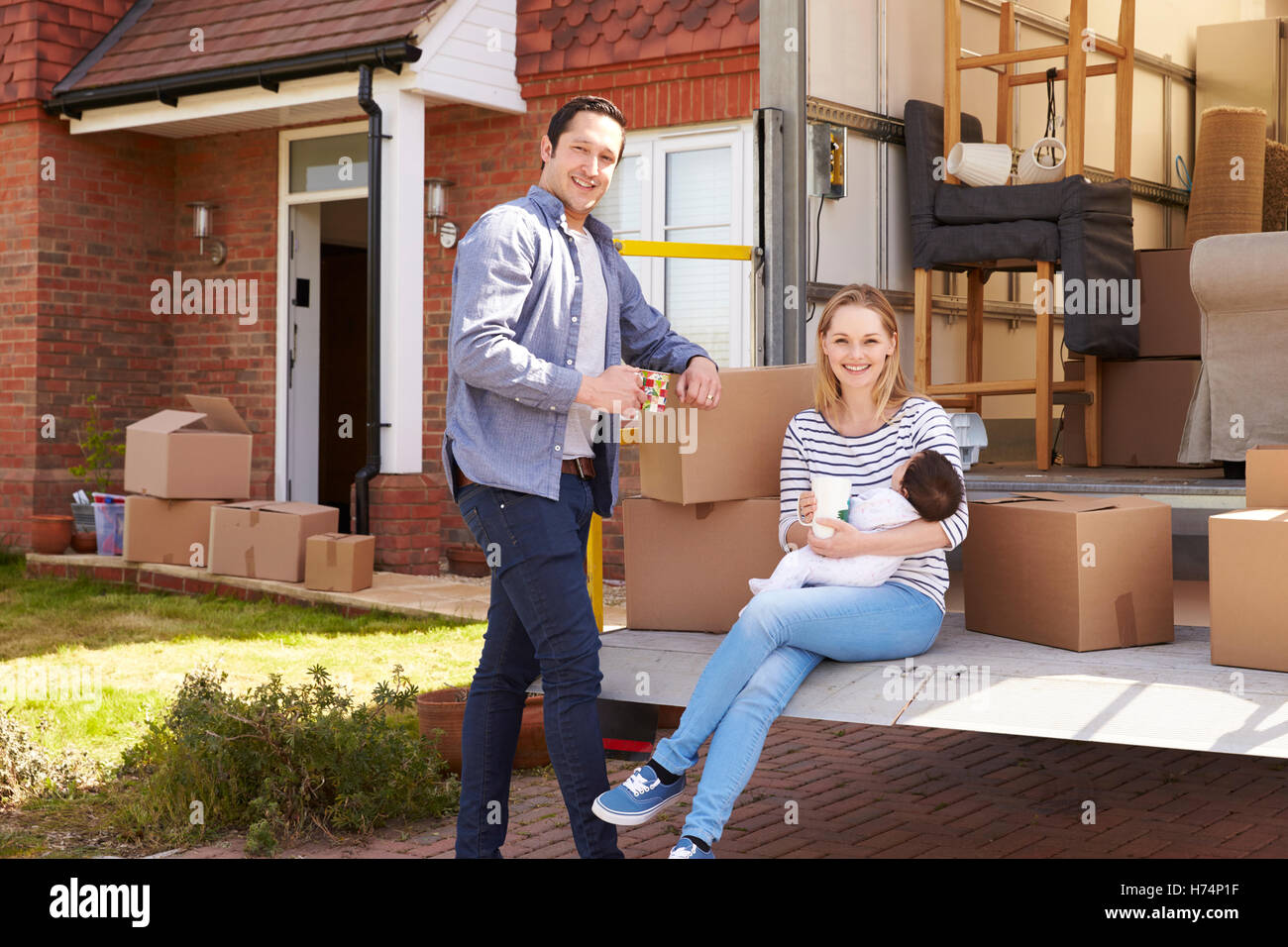 Family On Tail Lift Of Removal Truck Moving Home Stock Photo