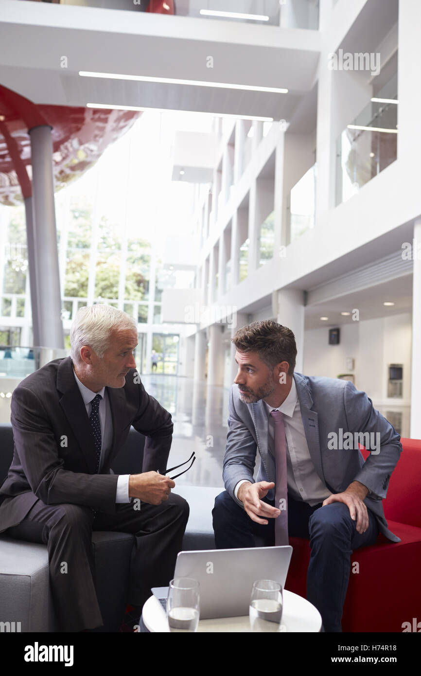 Two Businessmen Meeting In Lobby Area Of Modern Office Stock Photo - Alamy