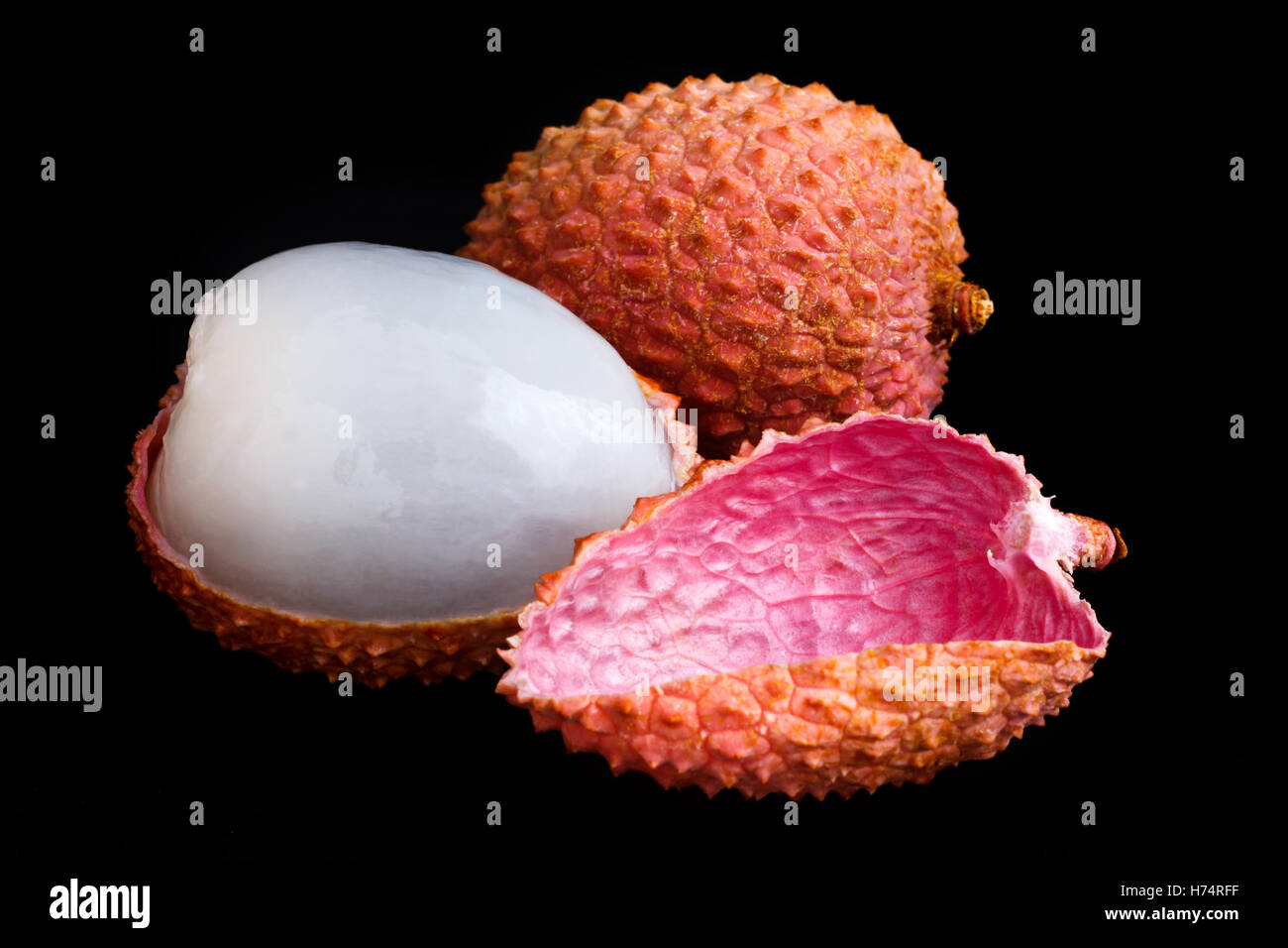 Single litchi with skin removed and flesh. On black. Stock Photo