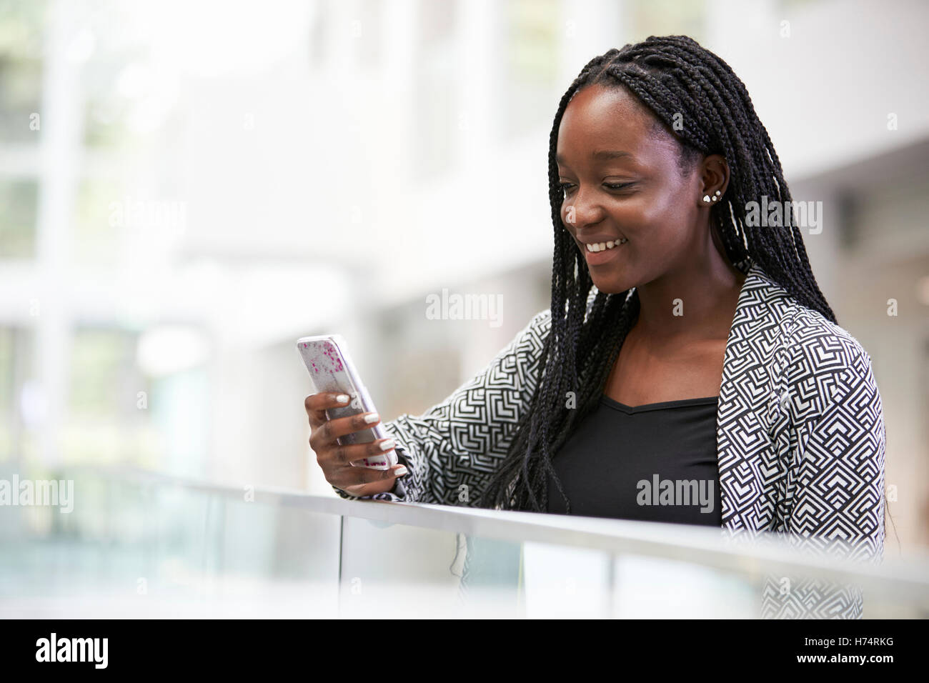 Young black female student using phone in university foyer Stock Photo ...