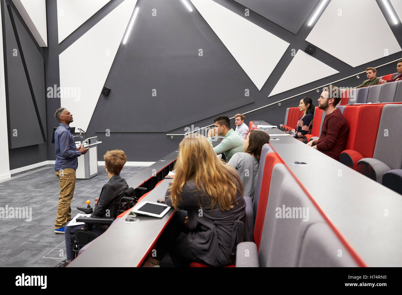 Man lectures students in lecture theatre, front row seat POV Stock Photo