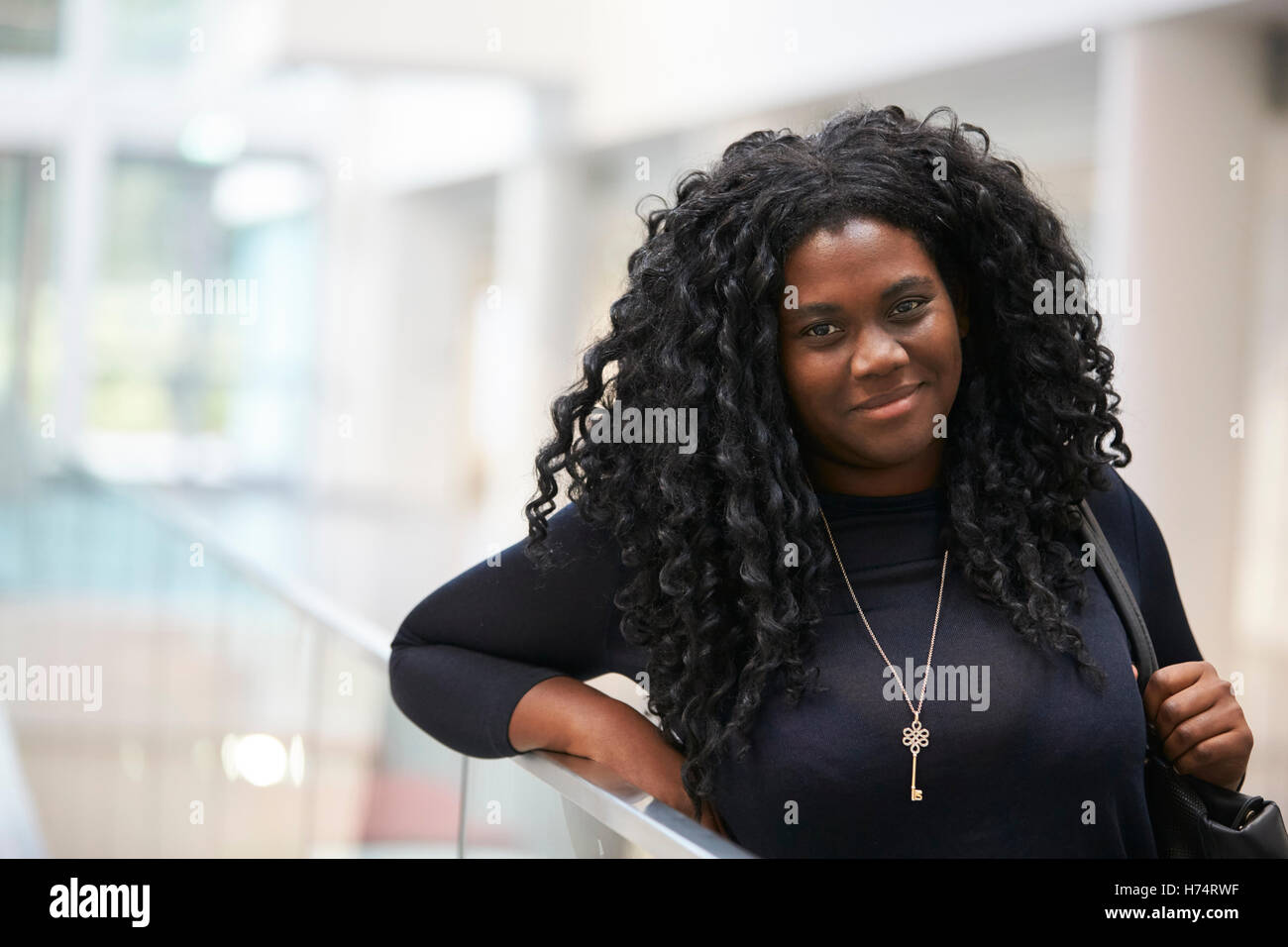 Smiling young black woman in the foyer of a modern building Stock Photo ...