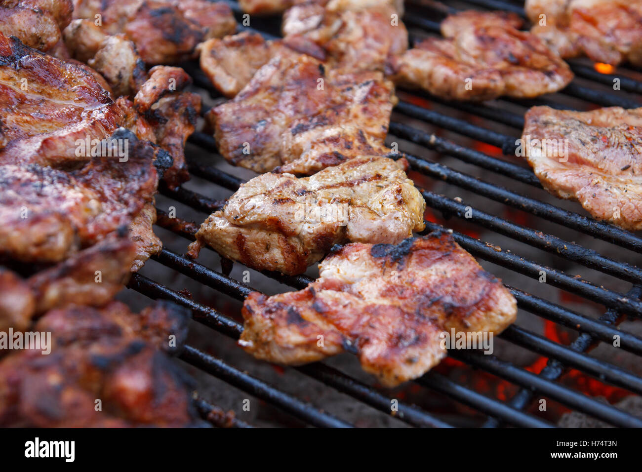 Many pieces of different kind of meat grilling on a barbeque grill. Selective focus. Stock Photo