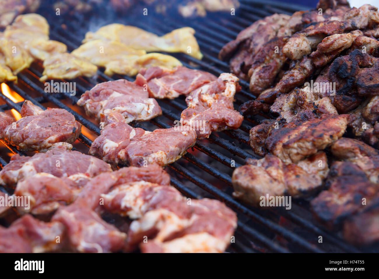 Many pieces of different kinds of meat grilling on a barbeque grill. Selective focus. Stock Photo